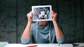 Online pets shops for small friends. Holds a tablet opposite his head. On the screen of the tablet is a portrait of a cat. Stress in self-isolation during coronavirus infection COVID-19.