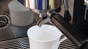 Barista pouring coffee stream from professional machine in cup.