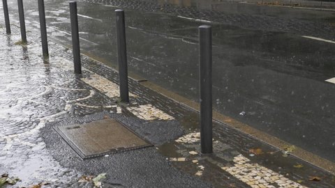 Paved sidewalk and bollards during summer rainfall. Low angle view. 
