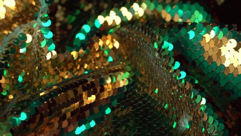 Fabric sequins gold and mint colors. Holiday abstract glitter background with blinking lights. Fashion luxury fabric glitter, spangles, paillettes