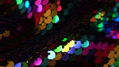 Multicolored sequins fabric. Holiday abstract glitter background with blinking lights. Fashion luxury fabric glitter, spangles, paillettes