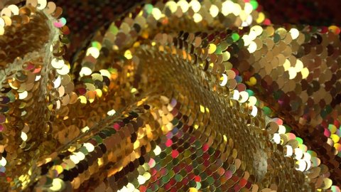Fabric sequins gold and colorful colors. Holiday abstract glitter background with blinking lights. Fashion luxury fabric glitter, spangles, paillettes