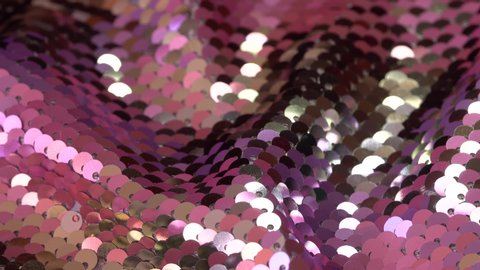 Fabric sequins pastel pink and silver colors. Holiday abstract glitter background with blinking lights. Fashion luxury fabric glitter, spangles, paillettes