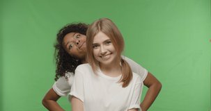 two beautiful girls posing and smiling on chroma key background . Happy multiracial women having fun on a Green Screen, Croma key, 4k raw video footage slow motion 60 fps