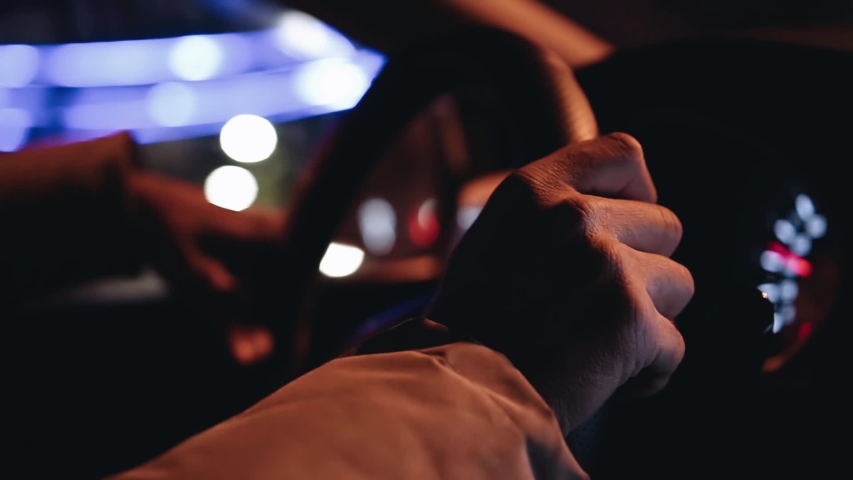 A man drives a car at night. Close-up of hands on the steering wheel. night highway.