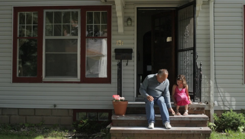Hispanic grandfather and granddaughter playing with and examining their pet