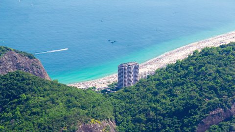 Aerial timelapse of Copacabana beach in Rio de Janeiro, Brazil. View of Leme behind the hills with jungle. People on the beach. Isolated building tower in front of the ocean