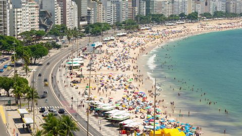 Rio de Janeiro, Brazil - January 16, 2020: Aerial timelapse of the Copacabana beach in Rio de Janeiro, Brazil. View of the busy beach full of people and tents, the ocean and the buildings.