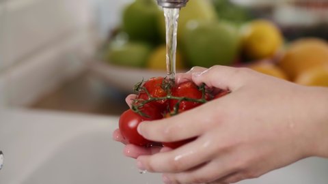 Handheld view of woman washing fresh and organic tomatoes