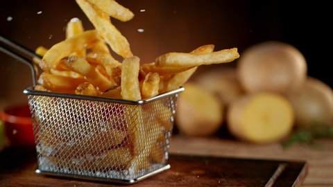 Super Slow Motion Shot of Falling Fresh French Fries on Wooden Table and Adding Salt at 1000fps.