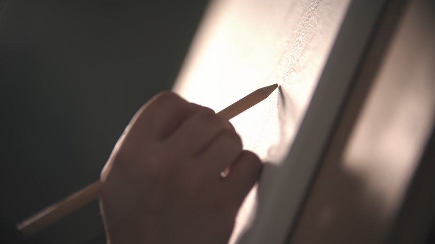 A hand of young woman sketching a tree on the canvas - bright sunlight