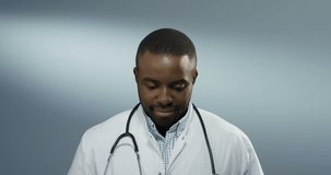 Portrait shot of the young African American handsome man physician or intern smiling joyfully to the camera. Close up.
