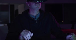 Front view of a Caucasian man working in a creative half lit office, wearing VR headset and touching virtual interactive screen late in the evening late in the evening