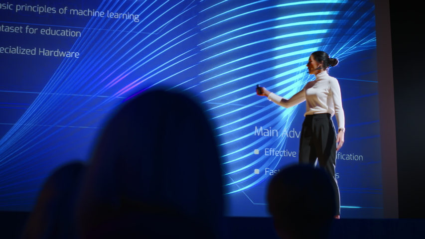 On Stage, Successful Female Speaker Presents Technological Product, Uses Remote Control for Presentation, Showing Infographics, Statistics Animation on Screen. Press Conference | Shutterstock HD Video #1045029661