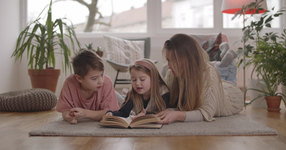 Mother daughter and son reading their favorite book on the floor in the living room