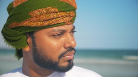 Close shot of an Omani man with wearing  omani traditional  dishdasha and  Musaar looking to the sea .