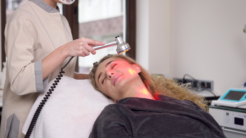 Slow motion of attractive proffesional female specialist which making ultrasonic peeling on lady's face in beauty center