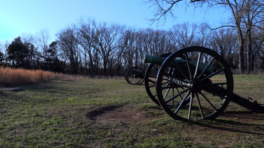 Video clip of slowly zooms in showing two civil war era cannons aiming down range as if waiting for the enemy to charge across the field in a late evening attack. 