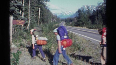 ALASKA USA-1977: People With Red And Blue Backpacks Hiking On Bright Sunny Day