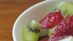 Pouring greek yogurt on fruit salad, slow motion video