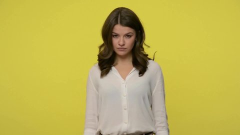 Impolite bully woman with brunette hair in blouse showing middle finger fuck off to camera, looking with aggression hatred disrespect, impolite behavior. studio shot isolated on yellow background
