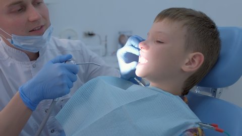 Preparing for fluoridation of teeth after hygienic cleaning of the oral cavity. Dentist drying child boy teeth with air to cover it with fluoride. Fluoridation of teeth after cleaning for protection.
