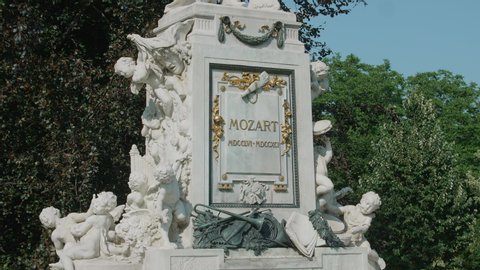 VIENNA AUSTRIA AUGUST 22 Wolfgang Amadeus Mozart monument, tripod shot of Mozart memorial in city center, camera tilting upwards from Mozart memorial tablet to statue, background tree with leaves