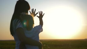 Happy family mom and daughter in field at sunset. Mom with daughter stretch their hand to sun while playing with rays. Concept of  happy family and togetherness with nature. Happy family concept - Powered by Shutterstock - Get 15% off with code: PIKWIZARD15