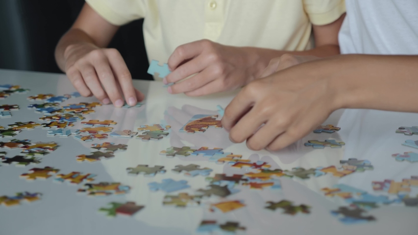 Two boys collect puzzles. Teamwork. Way to success. Happy family is engaged in self-development Royalty-Free Stock Footage #1045100821