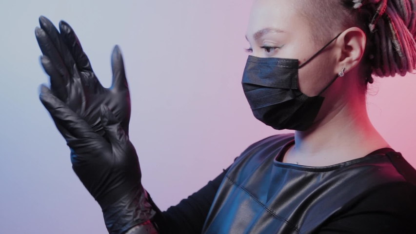 Young girl with dreadlocks puts on rubber gloves.