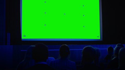 In the Modern Movie Theater Captivated Audience Watching New Blockbuster Film on Mock-up Green Screen. People Watching Video Game Tournament Streaming, Live Concert Video, New Product Release Trailer
