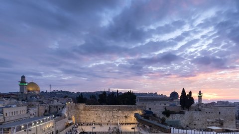 Timelapse of beautiful sunrise clouds moving over the Mount of Olives, the Western Wall and the Temple Mount, as Jewish people gather for morning prayer; Jerusalem Israel