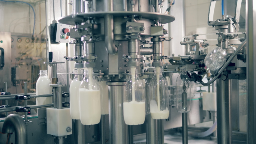 Transparent bottles are getting filled with milk by factory complex. Industrial factory equipment Filling Plastic Bottles Royalty-Free Stock Footage #1045107931