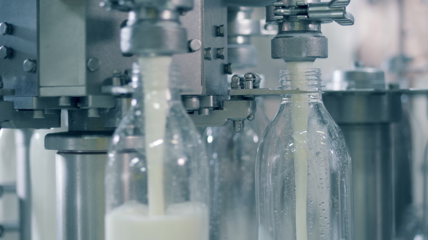 Factory conveyor is spinning and filling bottles with milk. Automated process of filling bottles with milk. Royalty-Free Stock Footage #1045107952