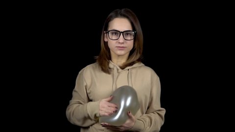 A young woman beats a balloon with water. The ball is shaking from blows. Woman holds a ball with vodo in her hands on a black background. Slow motion