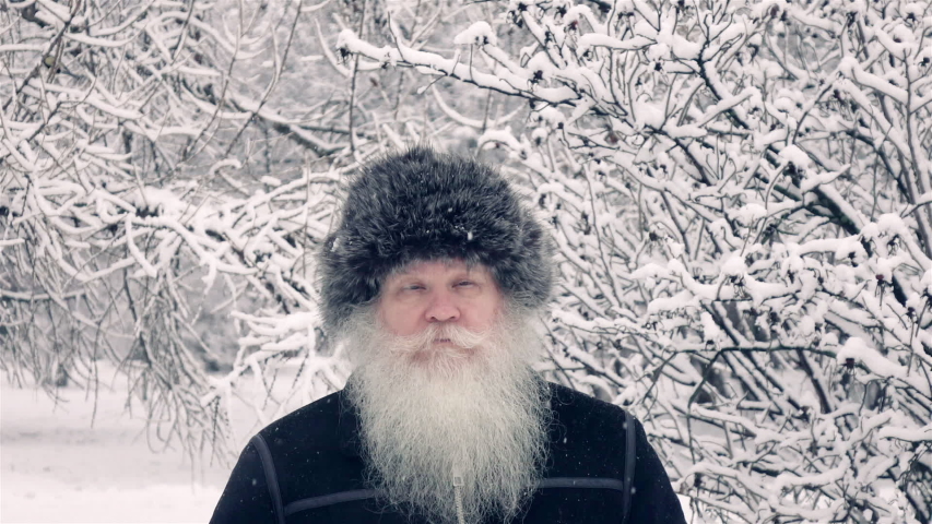 Elderly man jumping at winter snow-covered park in slow motion. Healthy cheerful senior retired person. 