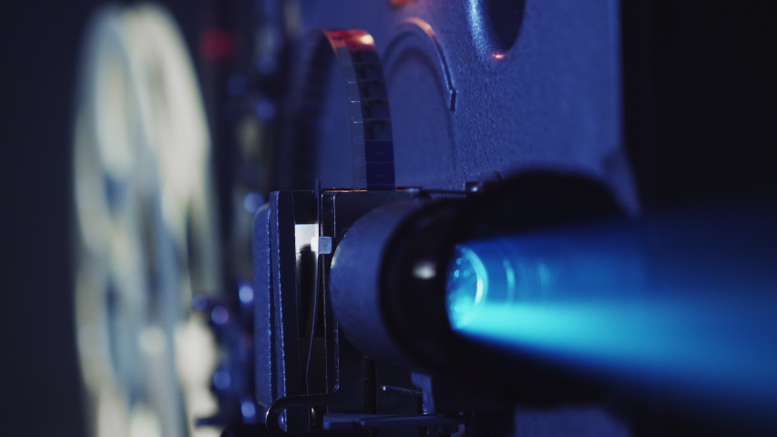 Close-up of an old film projector shows a film, the lamp flashes. Projector projecting a beam of light in a dark room Royalty-Free Stock Footage #1045111504