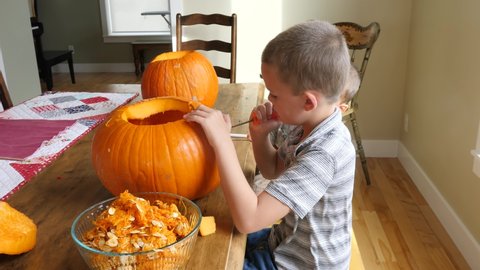 A family carving pumpkins for halloween at the kitchen table in their house
