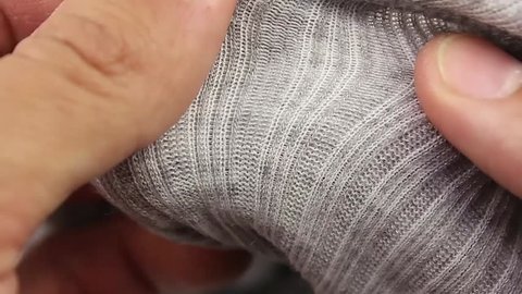 human hand testing gray wool thermal underwear, closeup(macro)