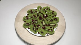Sliced kiwi fruit lined on a white porcelain dish served on a wooden board sprinkled with pomegranate seeds on it Awesome Awesome Conceptual fruit shoot tropical organic Vitamin C.
