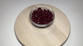 4K video Macro shot of tropical organic pomegranate fruit made of different perspective angles made of pomegranate seeds in transparent glass bowl on wooden board.
