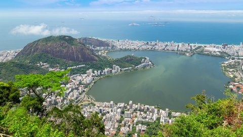 Aerial panorama timelapse of Rio de Janeiro, Brazil. View of Ipanema, Leblon, Lagoa lake, Copacabana, the beach and the ocean. Moor peak and mountains in the background. Jungle tree in front.