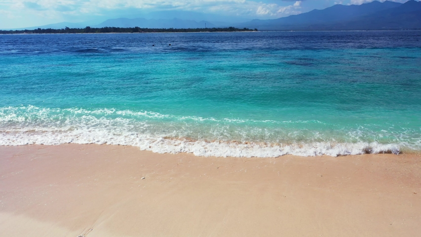 Waves rushing through the shores under the blue skies of El Nido Beach in the Philippines - Running Shot