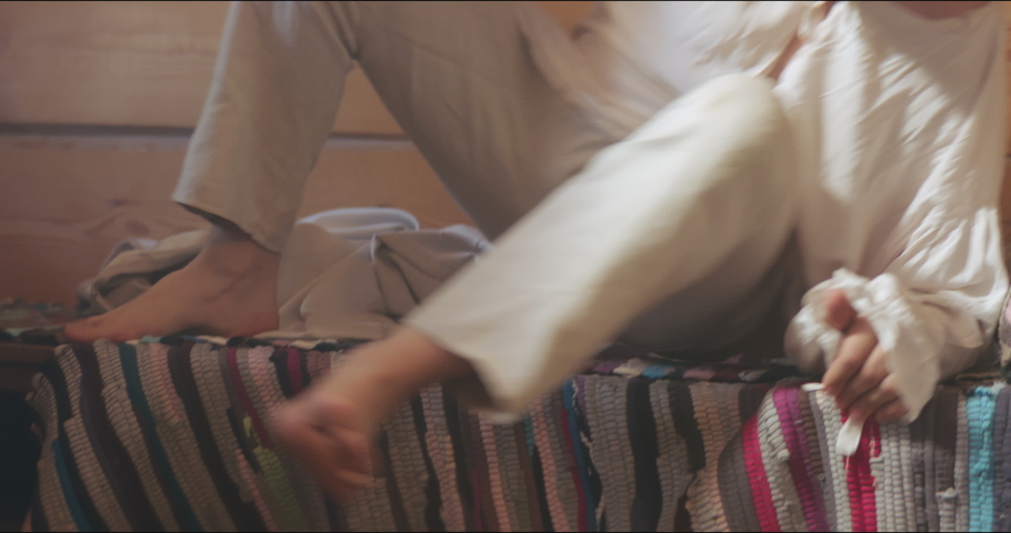 Close up of villager putting on bast shoes in his house.Historical reconstruction. 18 century. Europe.