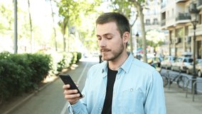 Satisfied man using smart phone in the street looking at camera with thumb up at the end