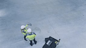 Industry 4.0 Modern Factory: Two Engineers Use Digital Tablet Computer with Augmented Reality Software Visualizing of Manufacturing Plant Room Mapping. Doing 3D Factory Floor Layout. High Angle Shot - Powered by Shutterstock - Get 15% off with code: PIKWIZARD15