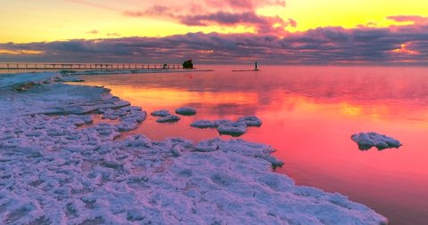 Icy red waters reflecting the Winter twilight sky, with lighthouse, moving aerial view. The colors are unaltered, exactly as my cameras recorded them. Lake Michigan sunrises can be intense.