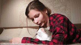 young girl close-up lying on the bed playing with a cat. authentic video, lifestyle. selective focus