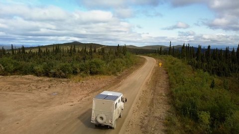 Aerial tracking shot of an off road camper van driving along the Taylor Highway in Alaska, USA