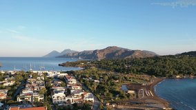 Aerial view video from flying drone of the black sand beach with yachts in small haven in Porto di Ponente, in Vulcano, Lipari and Salina Aeolian Islands on a summer at beautiful sunset with blue sky 